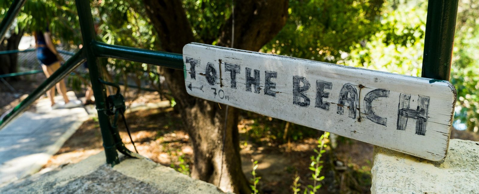 Wegweiser an einem Baum, handgemaltes Schild in Richtung Strand